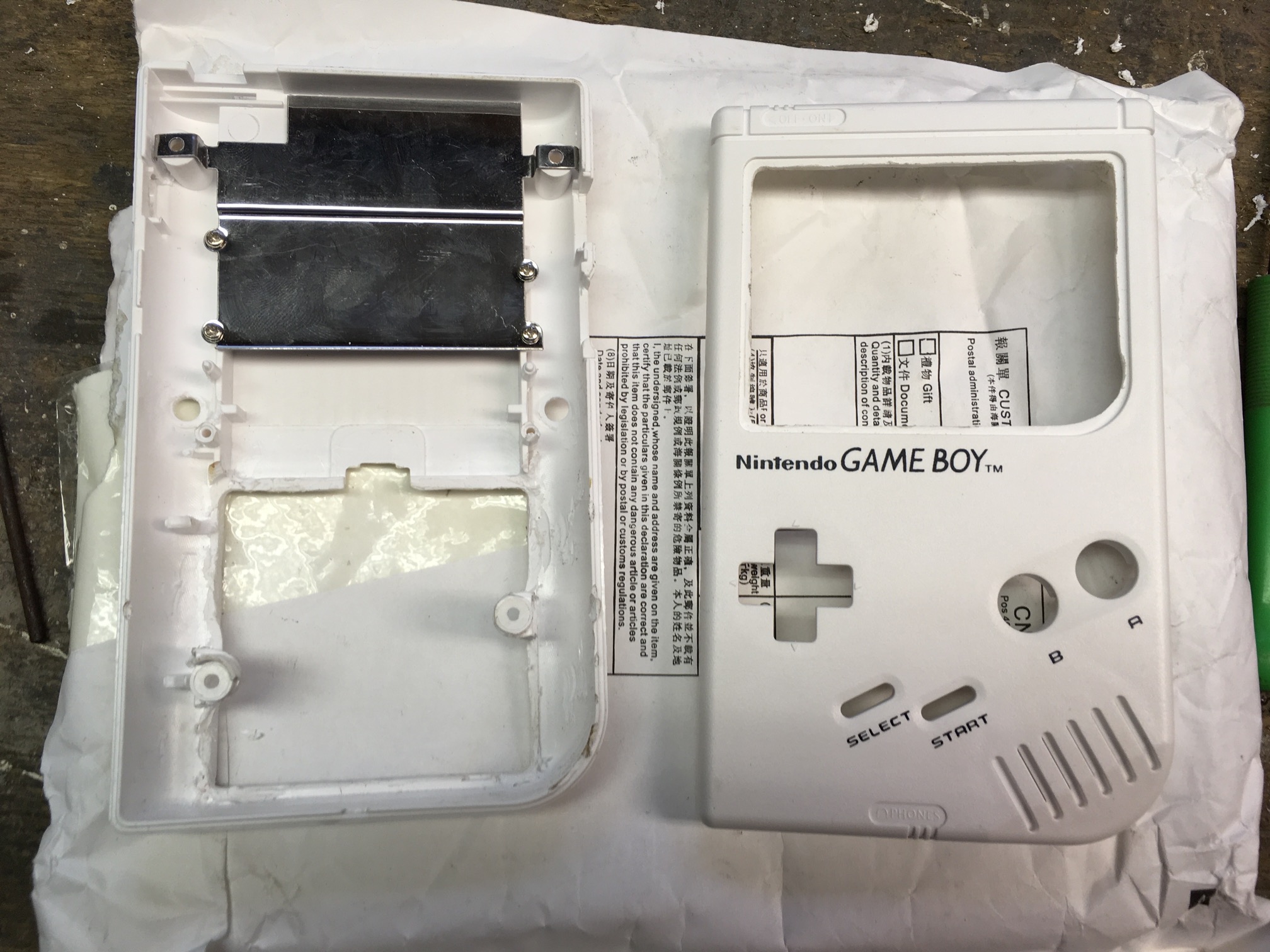 (Caption) Battery compartment removed, screen area extended and the middle screw posts grounded out. So instead of six screws, the whole case has to hold together using only four screws. The newly created space will be used for tactile switches for L and R buttons.