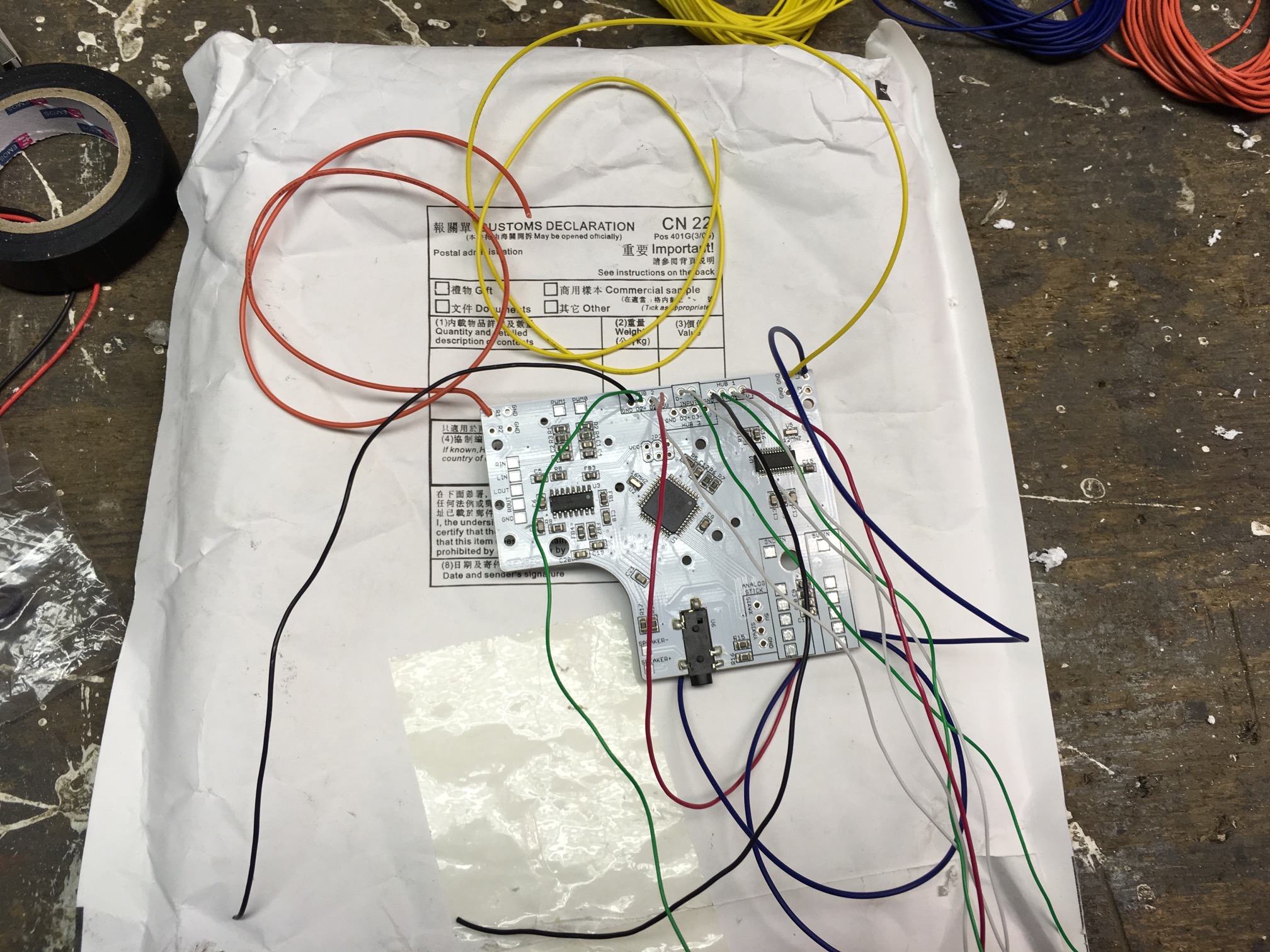 (Caption) Logic board with all through-hole wires soldered in! That allows us to mount it and handle all the surface mounted stuff later. This beauty not only takes care of converting all button presses into USB keyboard emulation via an Arduino compatible chip but also serves as an USB hub (I used two USB ports in my build), audio amplifier and low-pass filter and the power strip in the bottom right makes sure each component requiring electricity gets it.